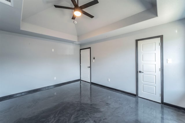 spare room featuring ceiling fan, a tray ceiling, and vaulted ceiling