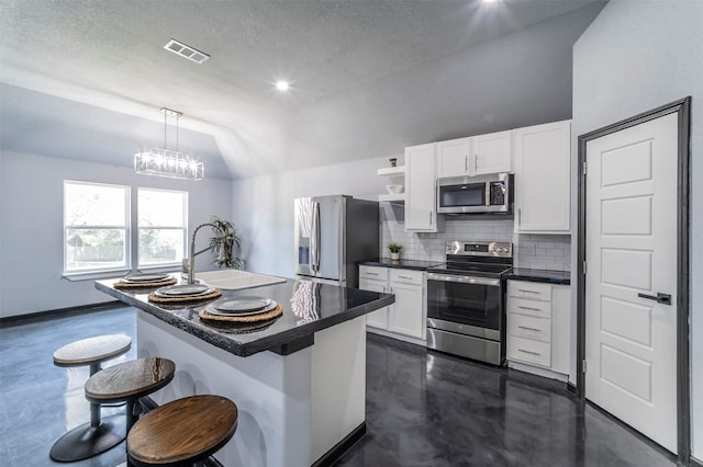 kitchen featuring a breakfast bar, lofted ceiling, sink, stainless steel appliances, and a center island with sink