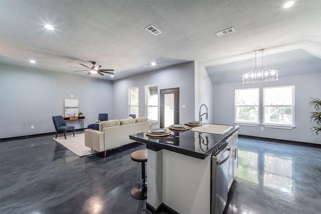 kitchen with sink, a kitchen breakfast bar, a textured ceiling, a center island with sink, and decorative light fixtures