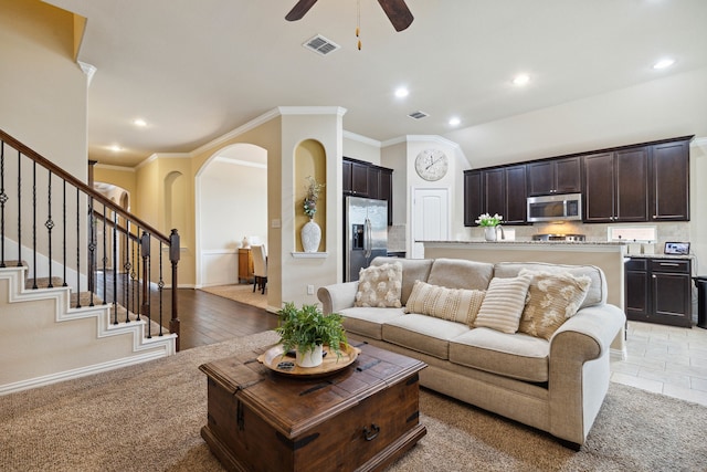 carpeted living room with ornamental molding and ceiling fan