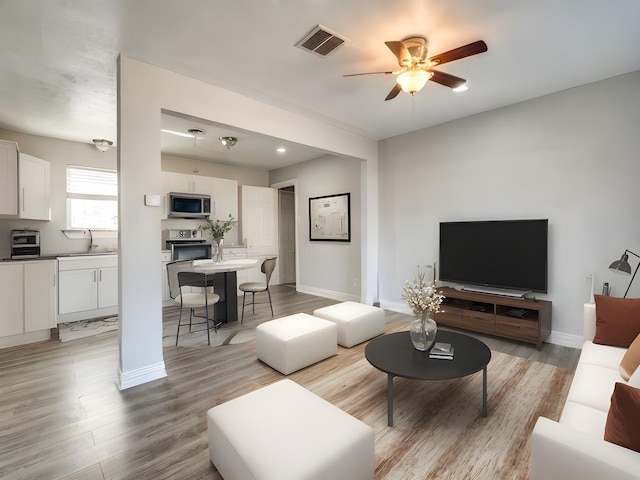 living room with sink, ceiling fan, and light hardwood / wood-style flooring