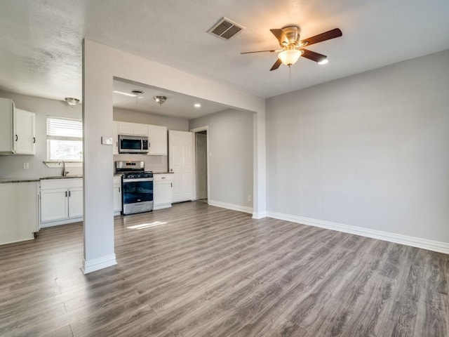 unfurnished living room with ceiling fan, sink, and light hardwood / wood-style floors