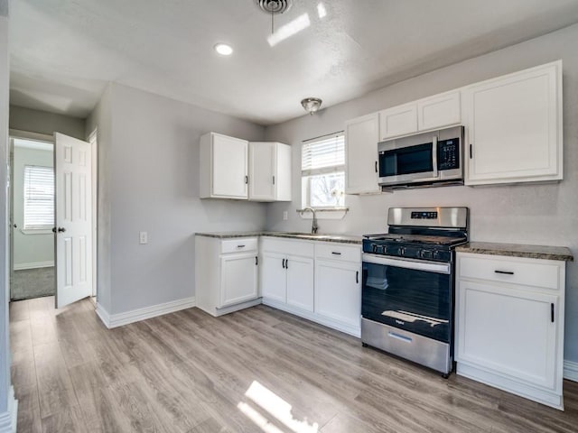 kitchen with white cabinetry, sink, stainless steel appliances, and light wood-type flooring