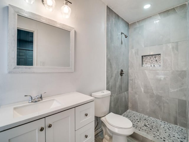 bathroom with vanity, toilet, and tiled shower