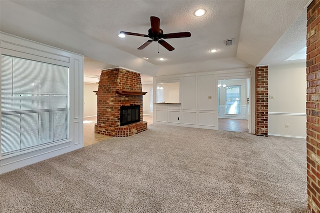 unfurnished living room featuring vaulted ceiling, a brick fireplace, light colored carpet, and a textured ceiling