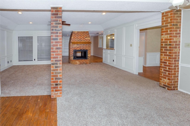 unfurnished living room with a brick fireplace, a decorative wall, and carpet floors