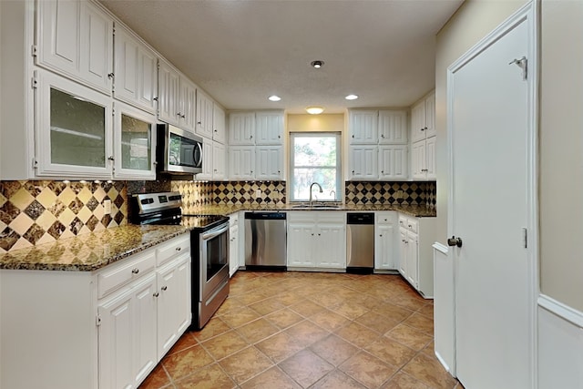 kitchen with sink, white cabinetry, appliances with stainless steel finishes, dark stone counters, and backsplash