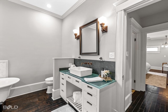 bathroom with wood-type flooring, vanity, crown molding, and toilet