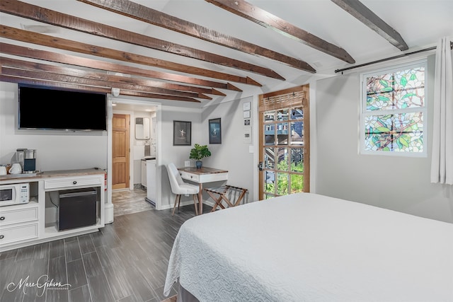 bedroom with dark hardwood / wood-style floors, ensuite bathroom, and beam ceiling