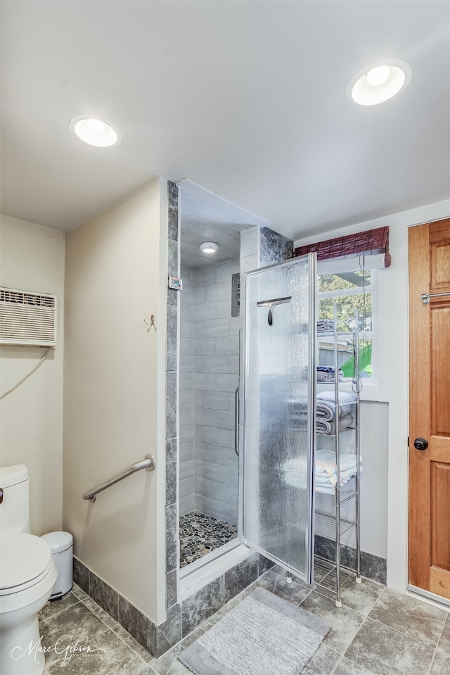 bathroom featuring an AC wall unit, an enclosed shower, and toilet