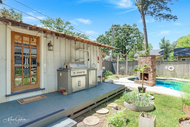 wooden deck with a fenced in pool, grilling area, and an outdoor stone fireplace