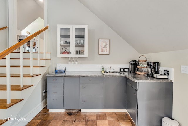 bar with lofted ceiling, sink, and gray cabinetry