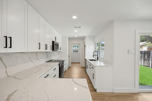 kitchen featuring sink, white cabinetry, appliances with stainless steel finishes, light stone countertops, and backsplash