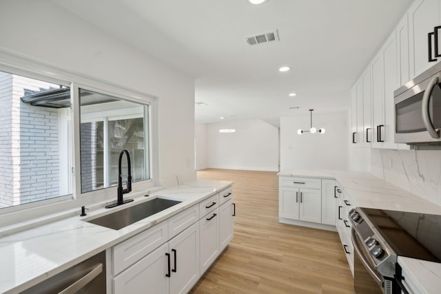 kitchen featuring sink, white cabinetry, decorative light fixtures, stainless steel appliances, and light stone countertops