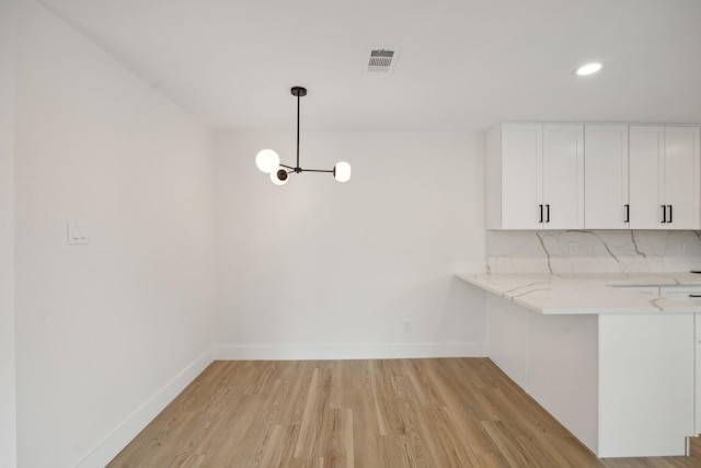 unfurnished dining area with a notable chandelier and light hardwood / wood-style flooring