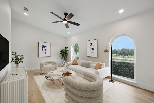 living room featuring plenty of natural light, lofted ceiling, ceiling fan, and light hardwood / wood-style flooring