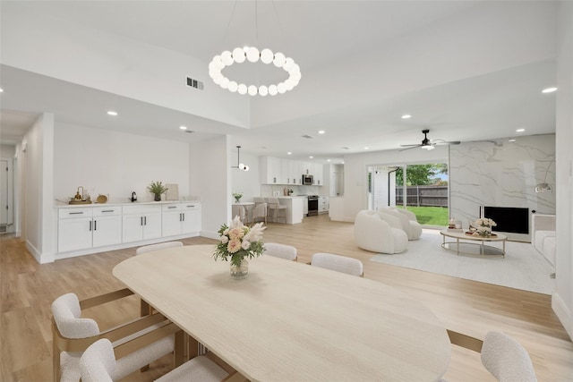 dining space with light hardwood / wood-style flooring, a premium fireplace, and ceiling fan