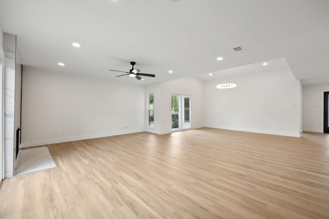 unfurnished living room with lofted ceiling, ceiling fan with notable chandelier, and light hardwood / wood-style flooring