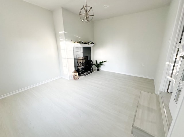 unfurnished living room with an inviting chandelier and hardwood / wood-style flooring