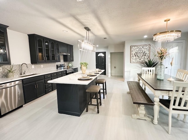 kitchen featuring sink, decorative light fixtures, stainless steel appliances, and a center island