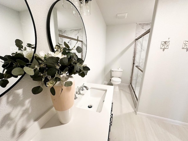 bathroom with vanity, a shower with shower door, and toilet