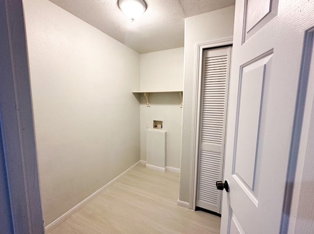 laundry area featuring a textured ceiling and light wood-type flooring