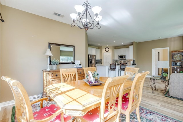 dining area with an inviting chandelier and light wood-type flooring