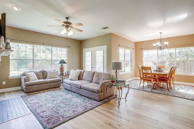 living room featuring french doors, ceiling fan with notable chandelier, and light hardwood / wood-style flooring