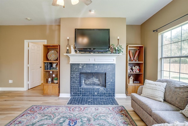 living room with a fireplace, light hardwood / wood-style floors, and ceiling fan