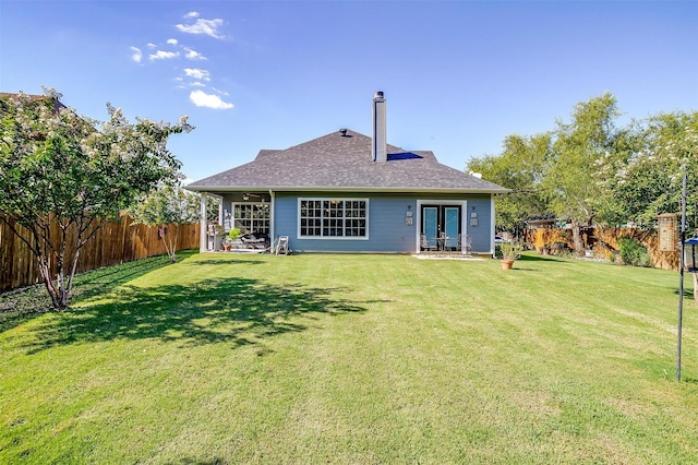 rear view of house with french doors, a patio, and a lawn