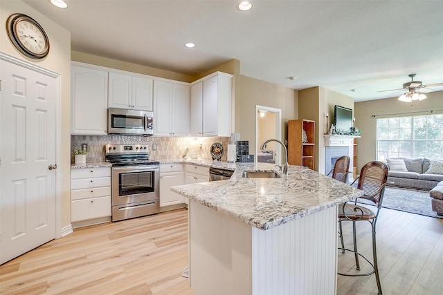 kitchen with a breakfast bar, sink, white cabinetry, kitchen peninsula, and stainless steel appliances