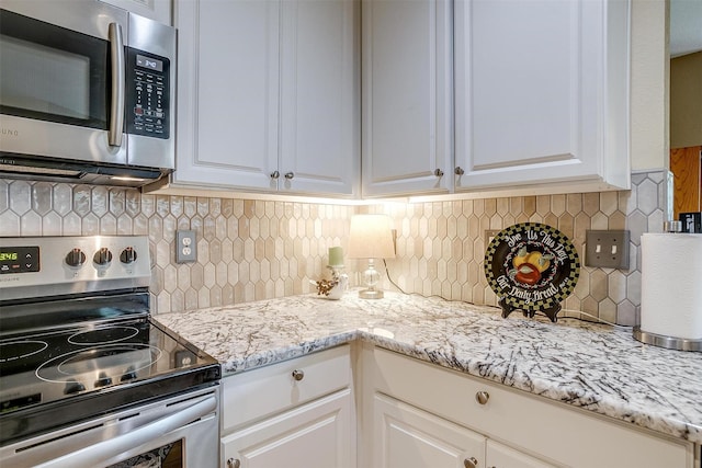 kitchen with backsplash, appliances with stainless steel finishes, and white cabinets