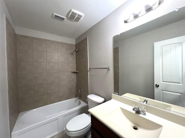 full bathroom with tiled shower / bath, vanity, toilet, and a textured ceiling