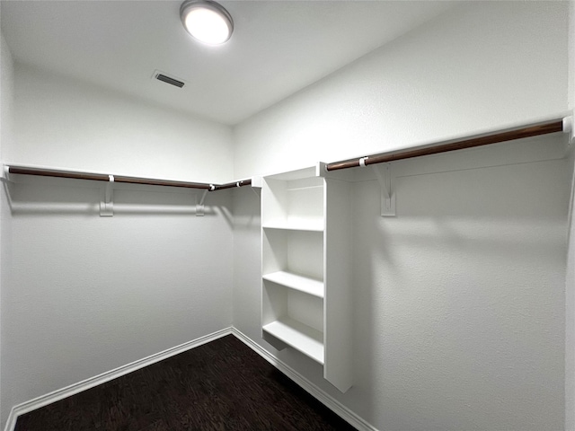 walk in closet with dark wood-type flooring