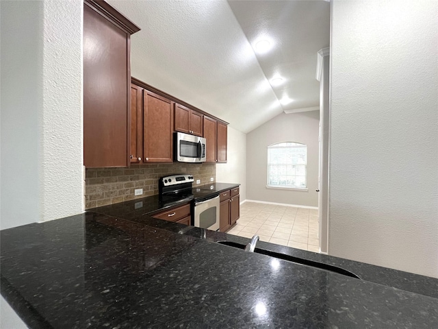 kitchen featuring lofted ceiling, dark stone countertops, stainless steel appliances, light tile patterned flooring, and decorative backsplash