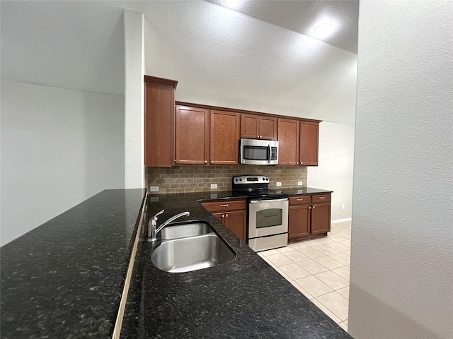 kitchen with light tile patterned flooring, sink, appliances with stainless steel finishes, dark stone counters, and decorative backsplash