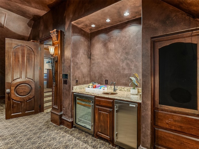 bar featuring sink, refrigerator, dark brown cabinets, dark colored carpet, and beverage cooler