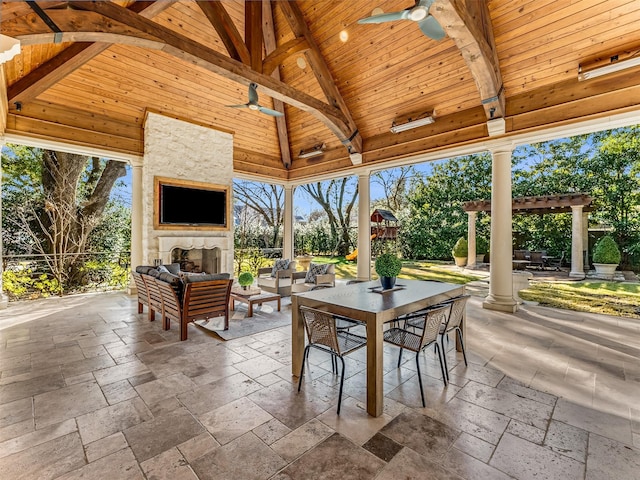 view of patio with a gazebo, ceiling fan, and an outdoor stone fireplace