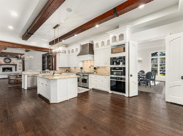 kitchen with premium range hood, appliances with stainless steel finishes, white cabinetry, hanging light fixtures, and a center island