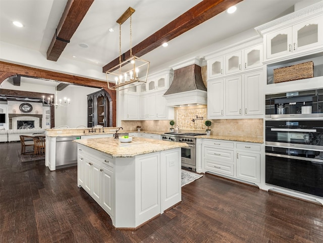 kitchen with stainless steel appliances, custom exhaust hood, a kitchen island, and white cabinets