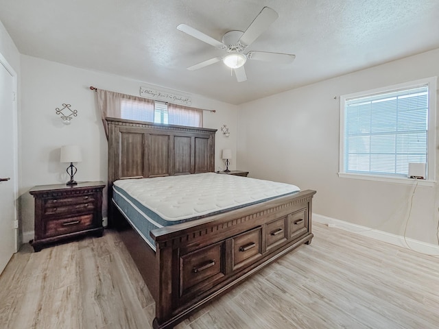 bedroom featuring a ceiling fan, baseboards, a textured ceiling, and light wood finished floors