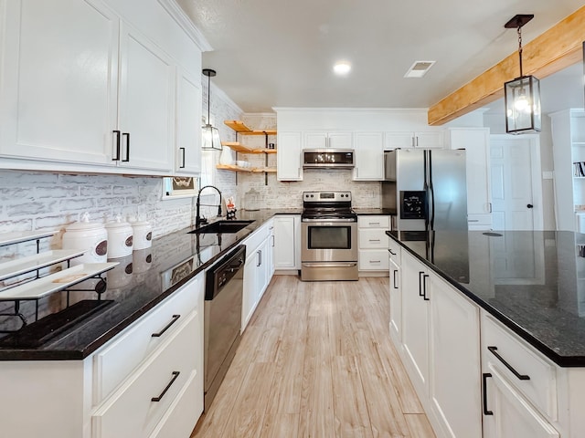 kitchen featuring light wood-style flooring, stainless steel appliances, a sink, white cabinets, and tasteful backsplash