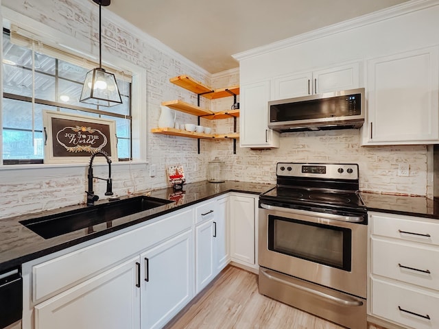 kitchen with white cabinets, ornamental molding, stainless steel appliances, and a sink