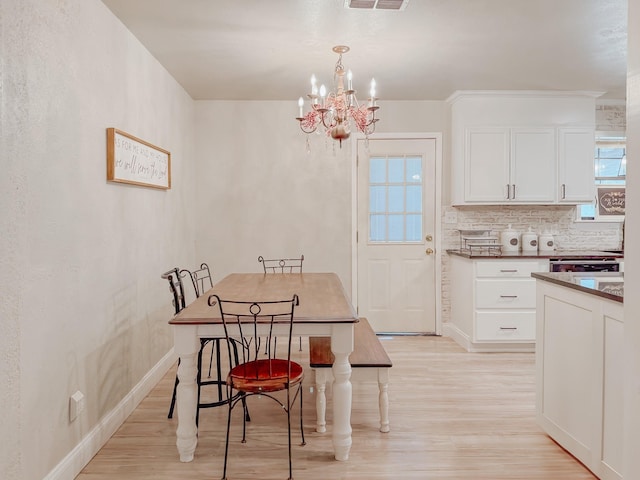 dining room with a chandelier, baseboards, visible vents, and light wood-style floors