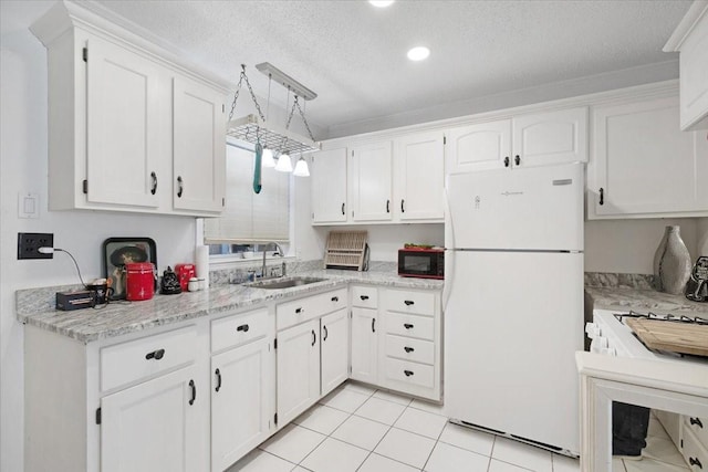 kitchen with light tile patterned flooring, sink, white fridge, and white cabinets