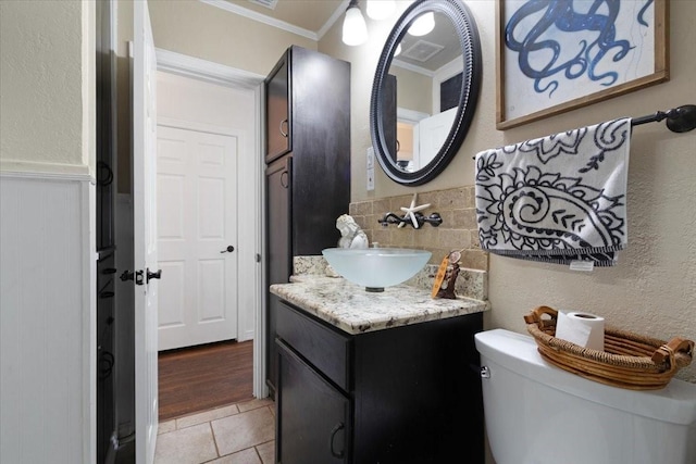 bathroom featuring vanity, backsplash, crown molding, and toilet