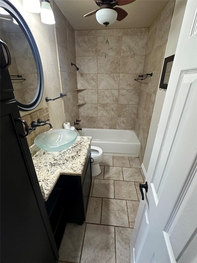 full bathroom with ceiling fan, tiled shower / bath, vanity, and toilet