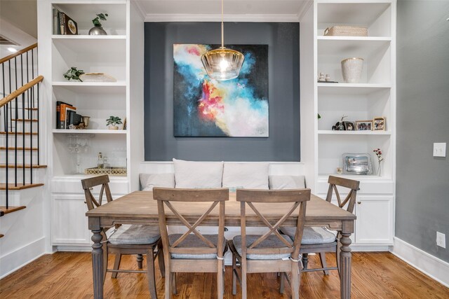 dining space with breakfast area, built in shelves, light hardwood / wood-style flooring, and ornamental molding