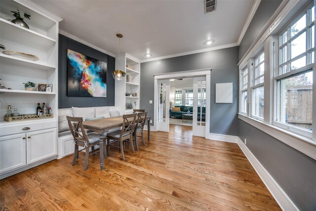 dining room with crown molding, built in features, light hardwood / wood-style flooring, and french doors