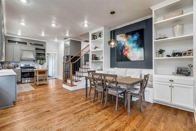 dining room with crown molding, built in features, and light wood-type flooring